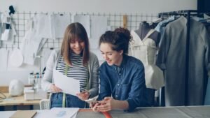 Two fashion designers working together on a project in their workshop.